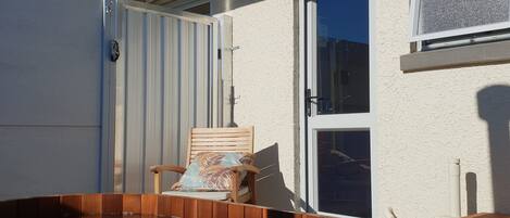 A residential backyard with a wooden deck, a sliding glass door, and a window.