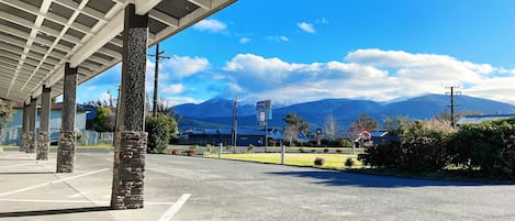 Un estacionamiento con un paseo techado, pilares de piedra y vistas a montañas al fondo.