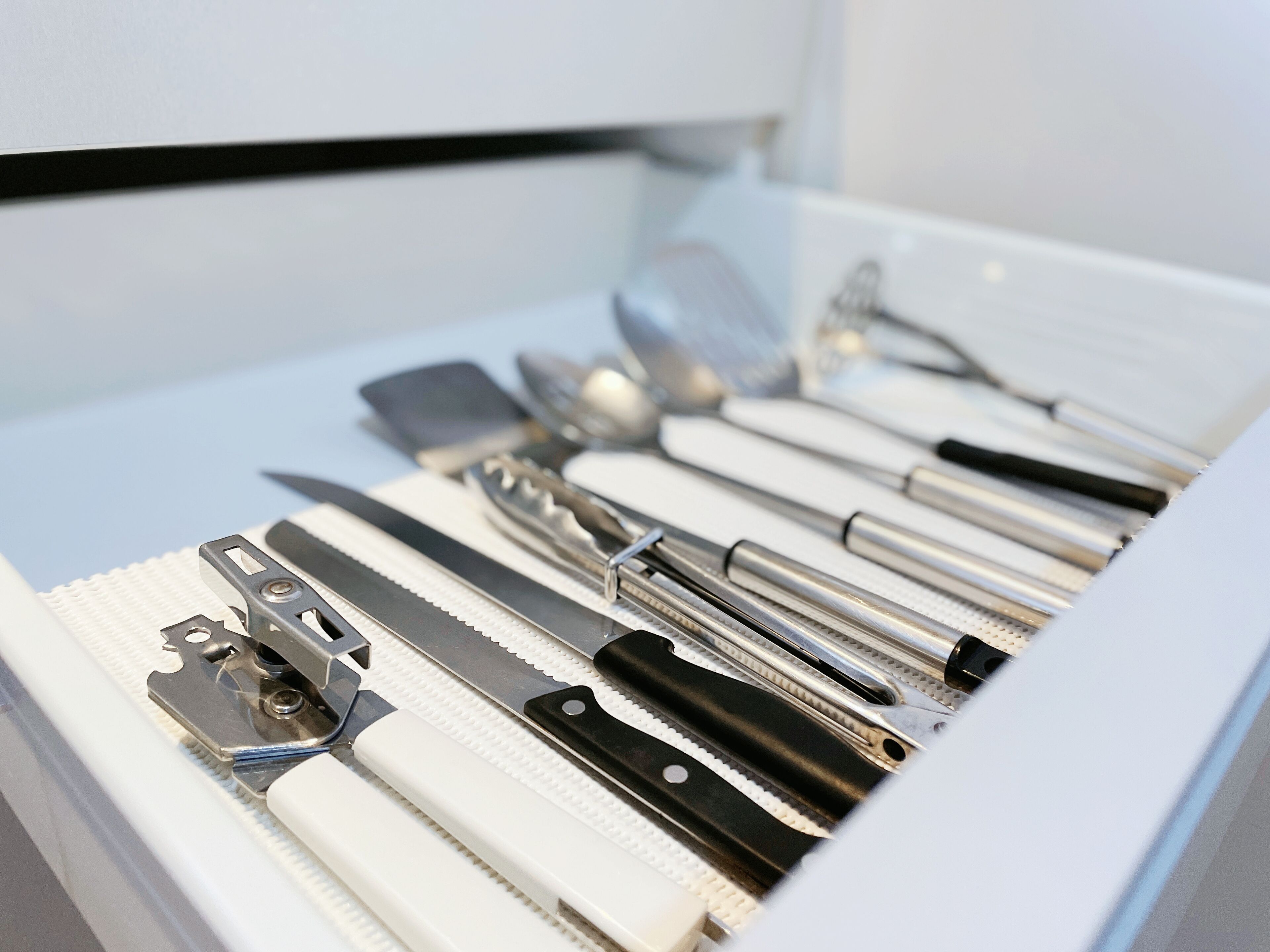 Un tiroir contenant divers ustensiles de cuisine, notamment des couteaux, des cuillères et des spatules.