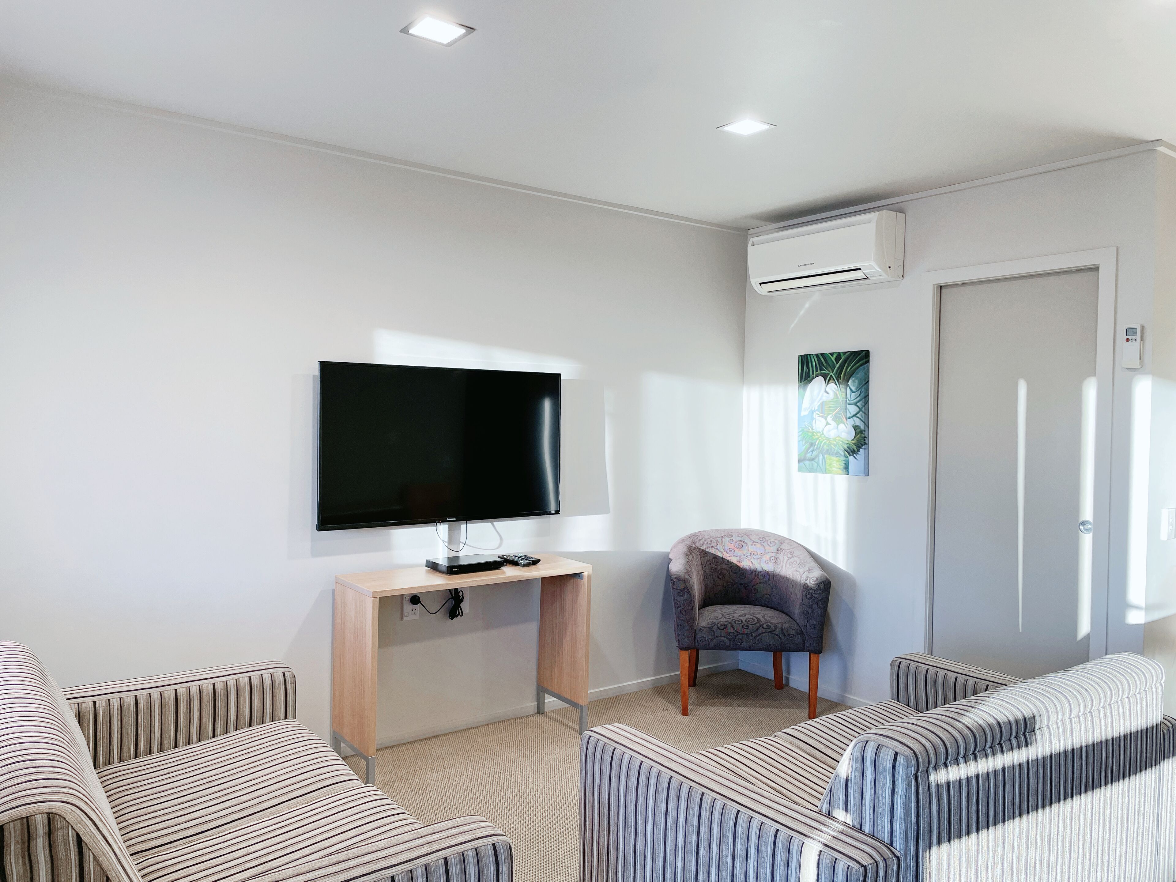A modern room with a flat-screen TV, a desk, a chair, and a sofa.