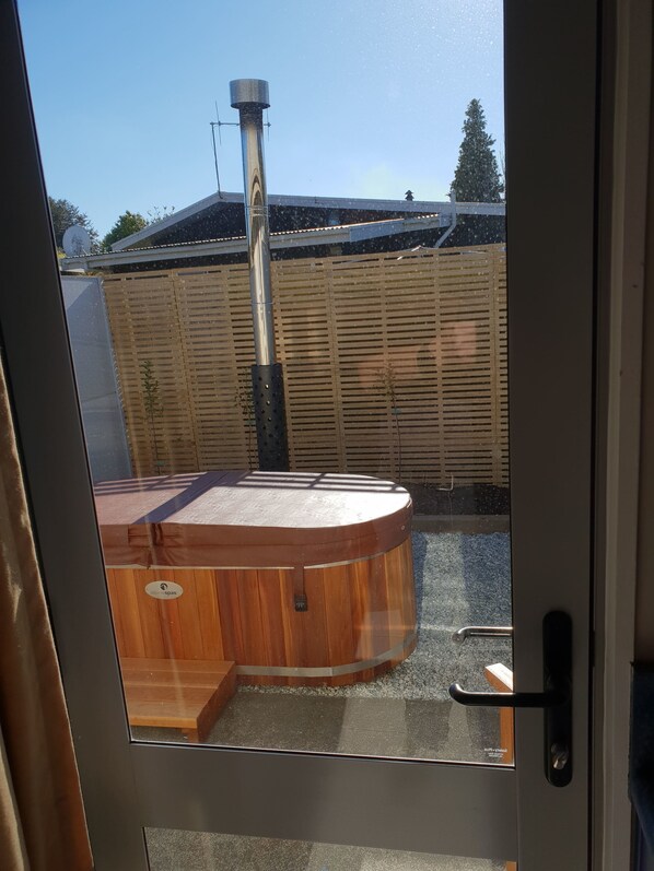 A wooden hot tub with a metal pole in a backyard. - Anchorage Motel Apartments (Te Anau)
