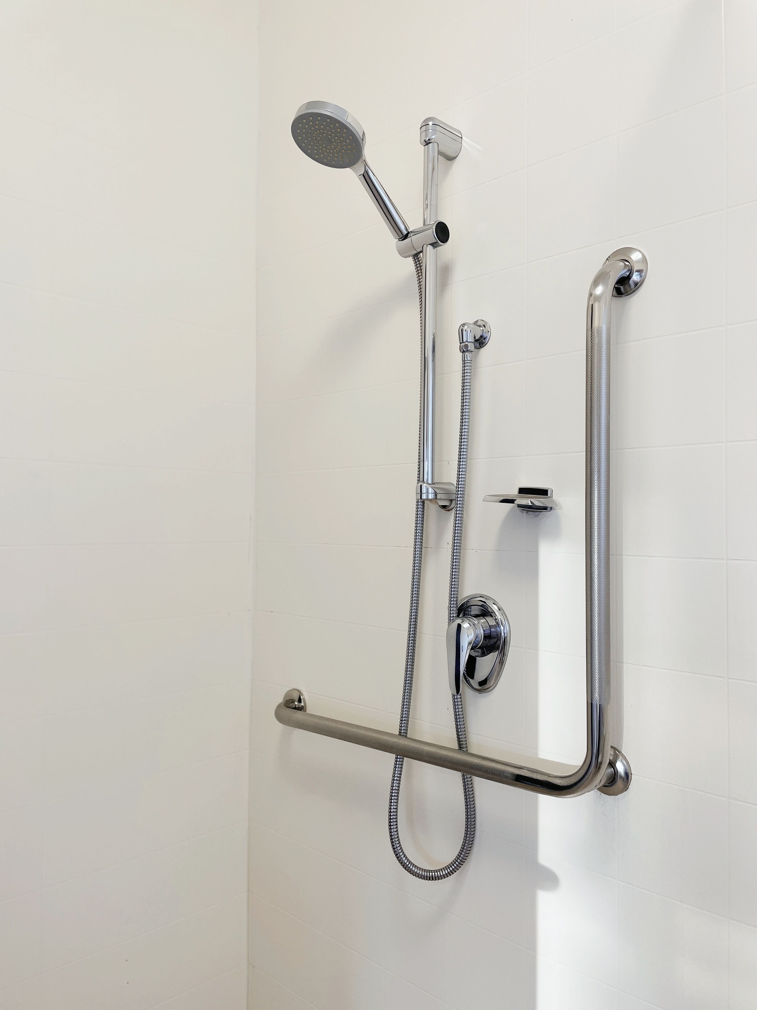Een douche met een handdouche, een douchekop en een douche slang.