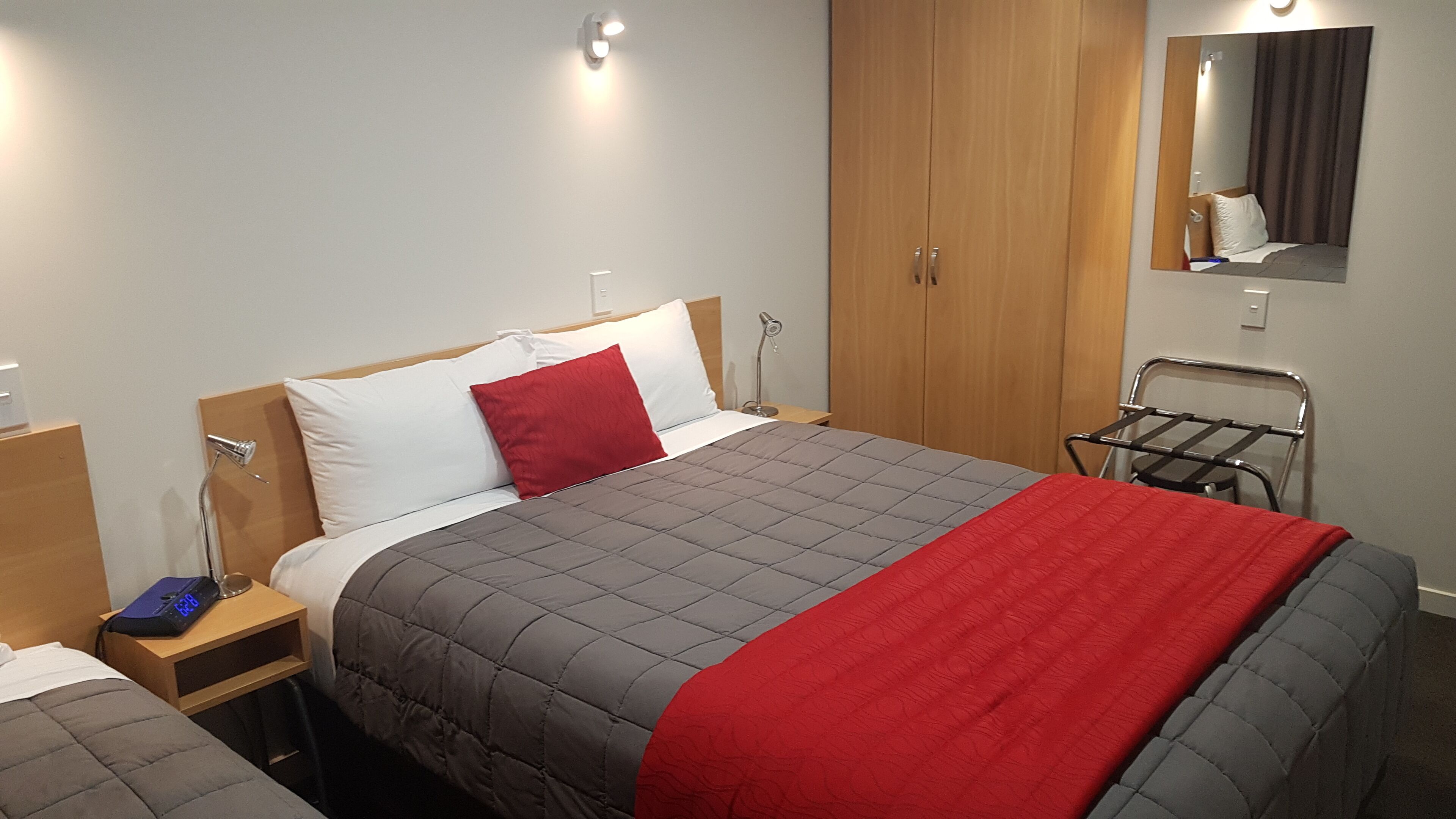 A hotel room with a bed, a nightstand, a bedside lamp, a wardrobe, and a mirror.