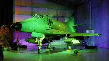 A green military aircraft on display in a hangar.