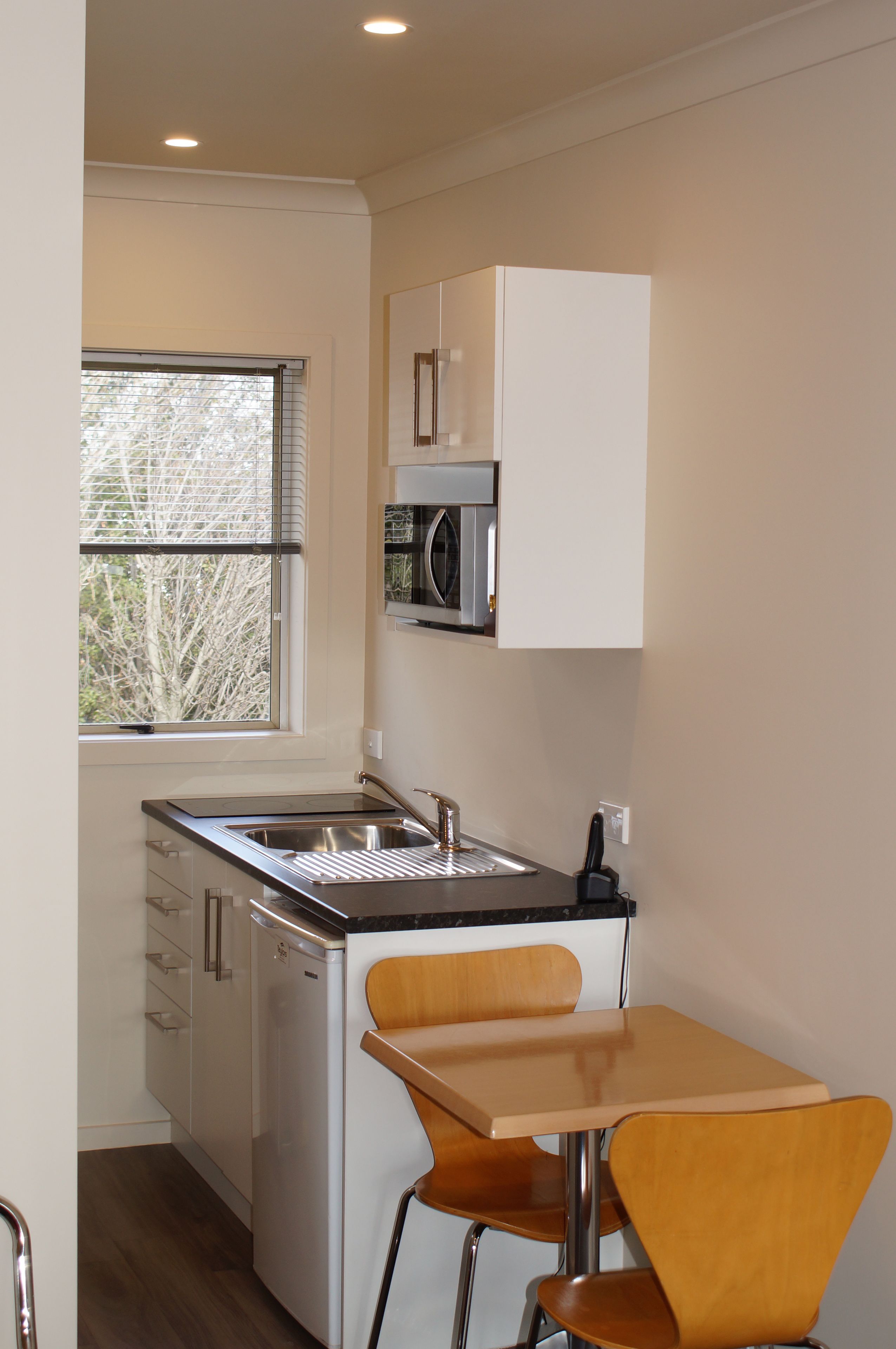 A compact kitchen with a sink, a microwave, and a small dining area with two chairs.