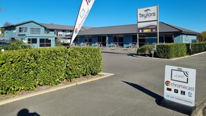 Un motel con un letrero que dice 'Taylor's Motel' y un rótulo de 'chromecast' que indica servicios de transmisión disponibles.