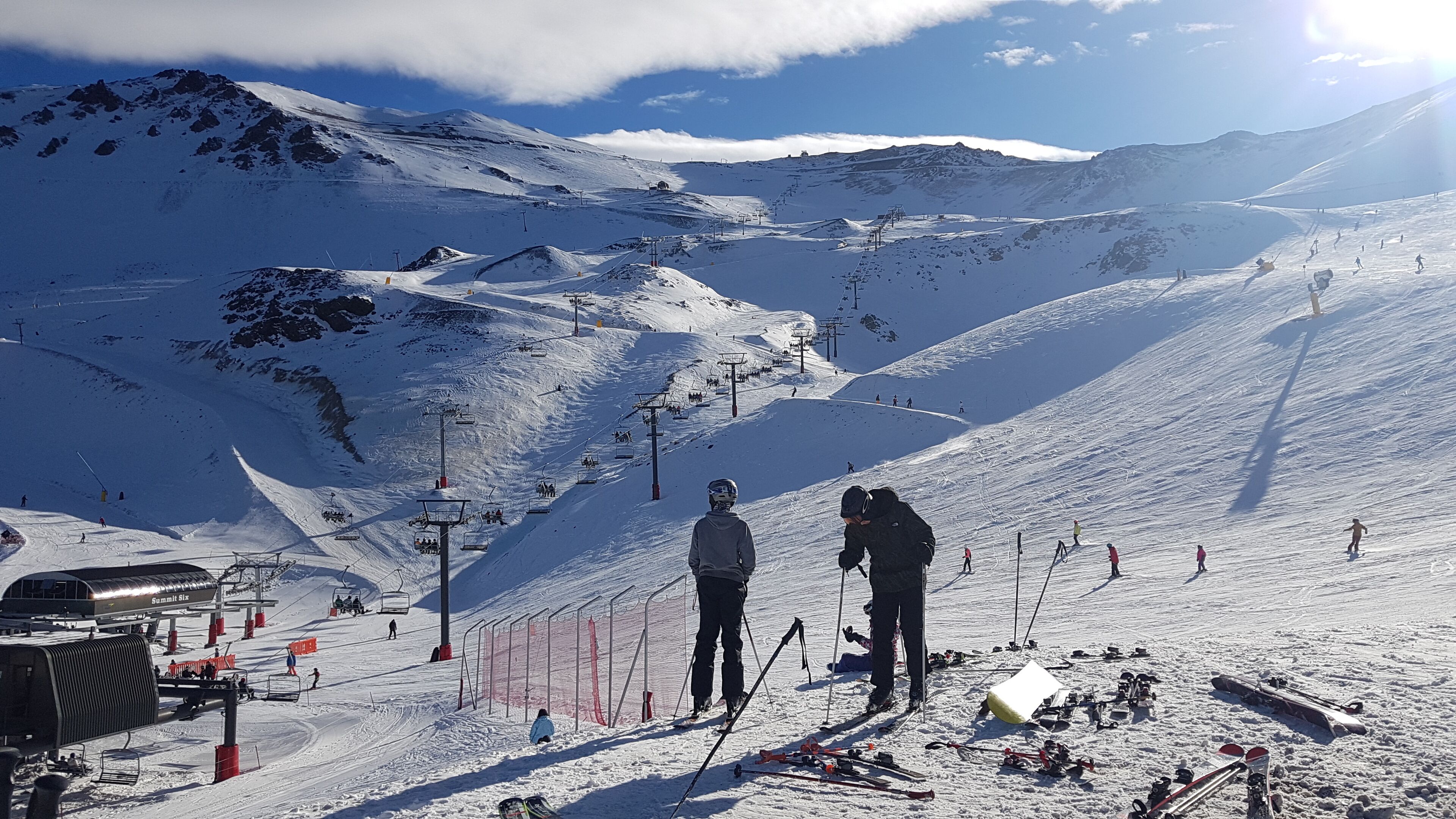 A ski resort with a chairlift, ski slopes, and a mountain backdrop.