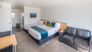Una habitación de hotel moderna con una cama grande, un sofá, un escritorio y un cuadro en la pared.