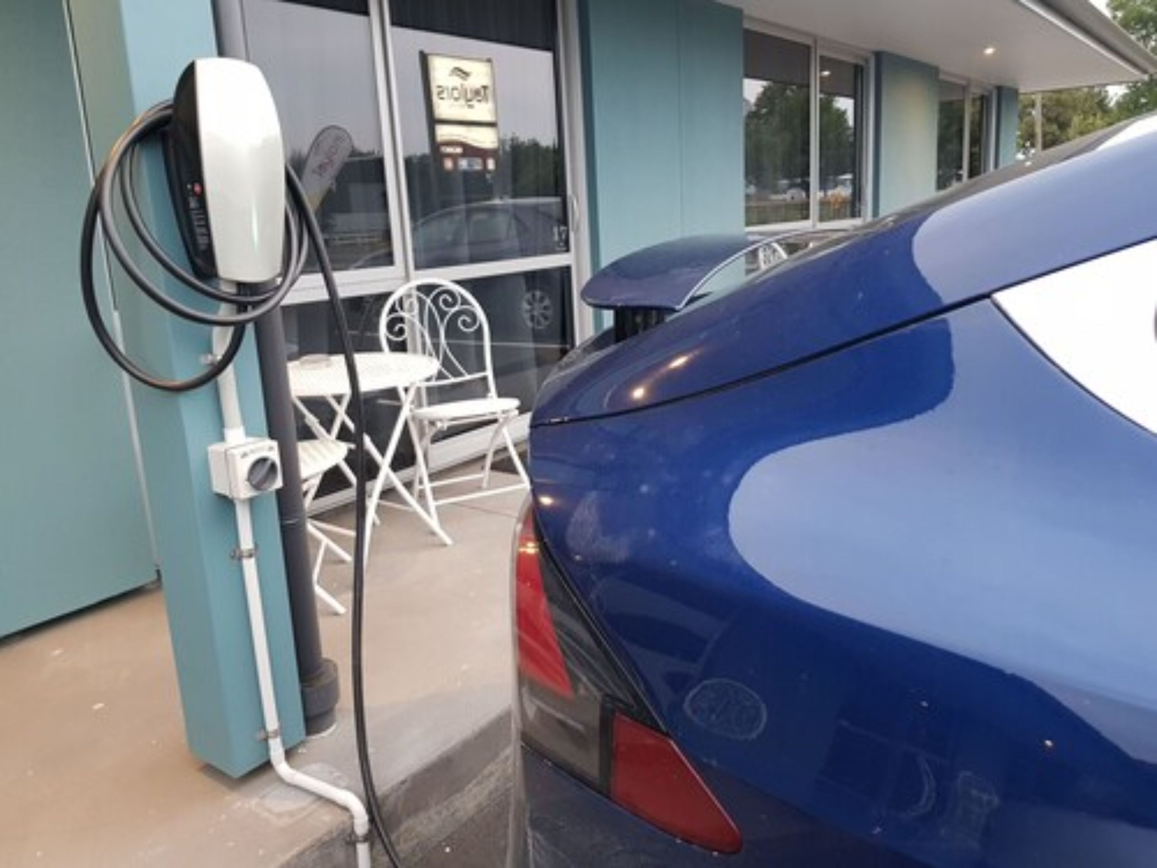 A blue car parked at an electric vehicle charging station.
