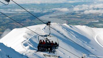A ski lift with passengers ascending a snowy mountain.
