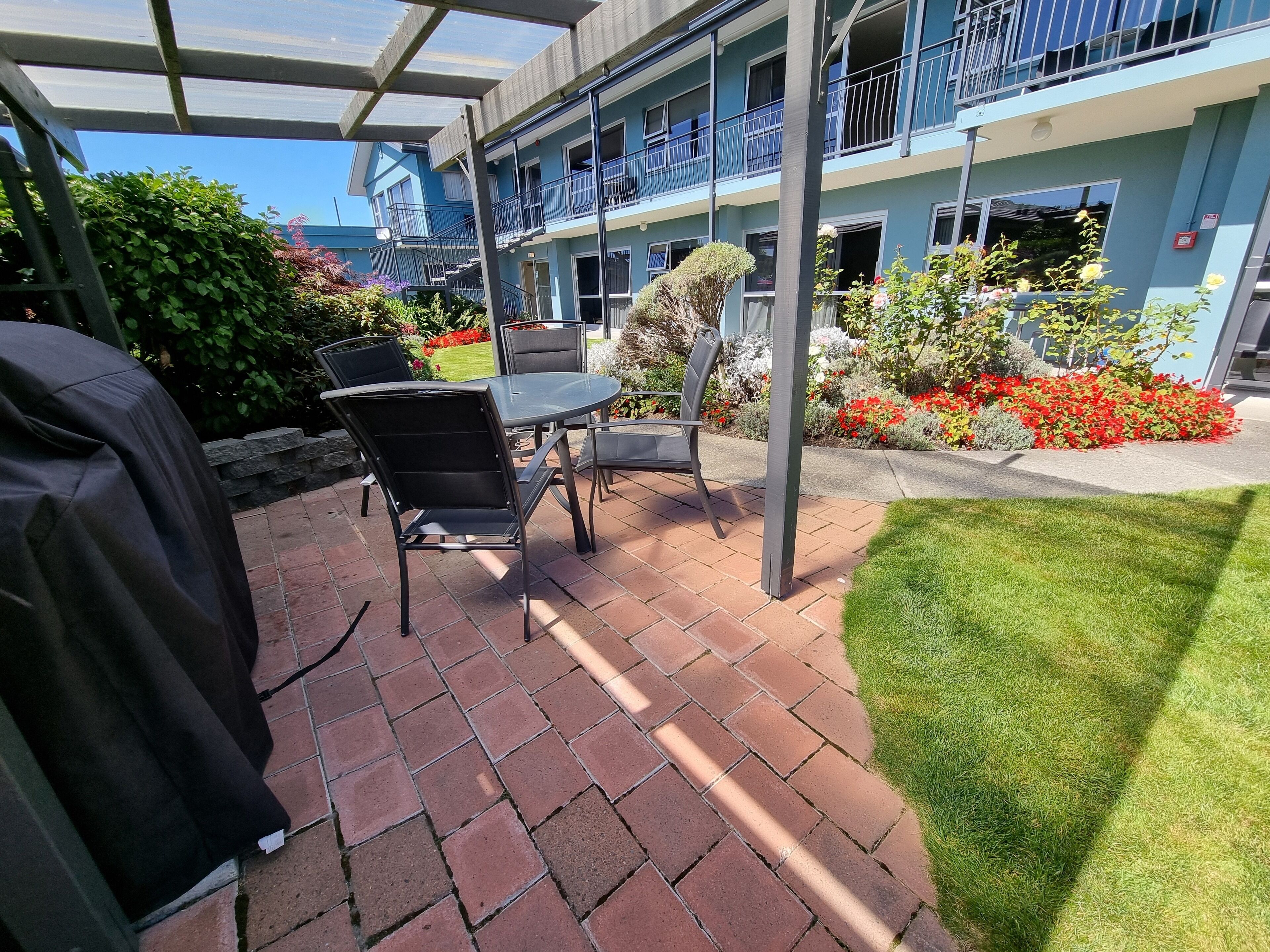 An outdoor patio area with a grill, chairs, and a table.