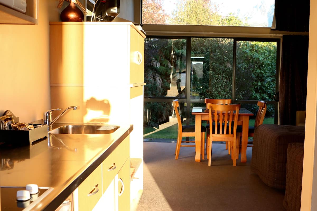 A compact kitchen with a sink, wooden cabinets, and a dining area with a table and chairs.