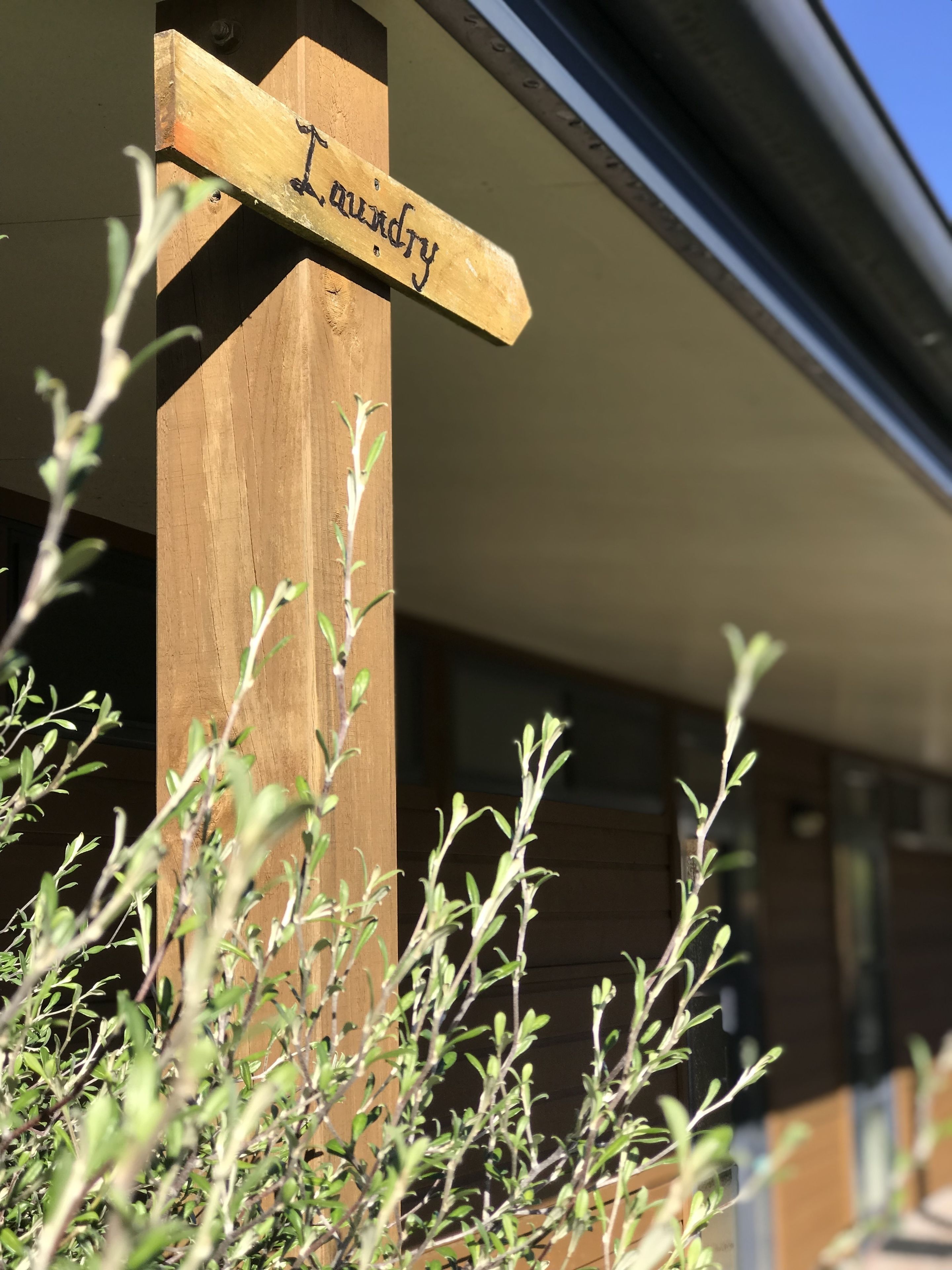 Une enseigne en bois portant le mot « blanchisserie », fixée à un poteau en bois.