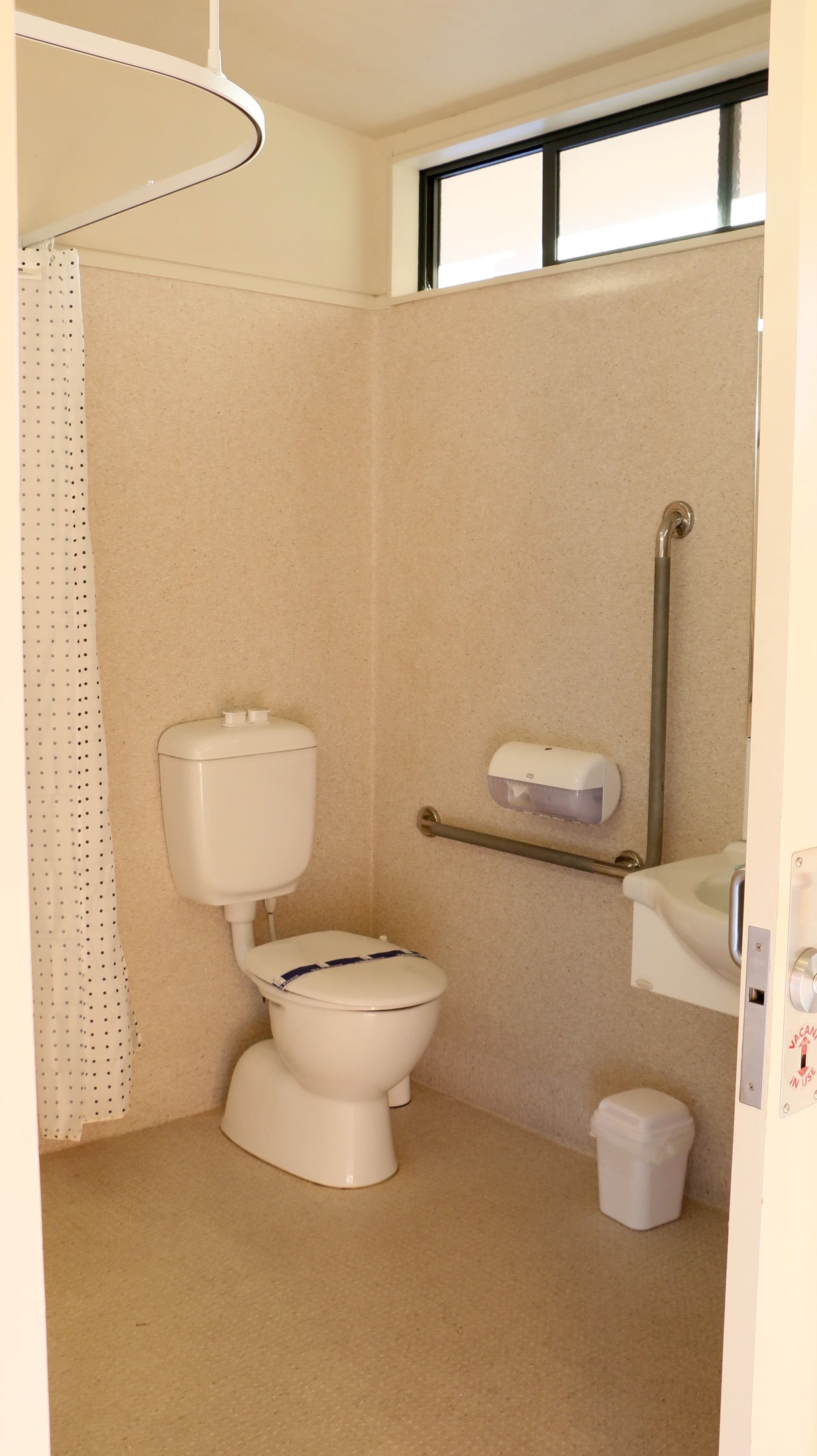 Une petite salle de bain compacte comprenant des toilettes, un espace douche et un sèche-mains.