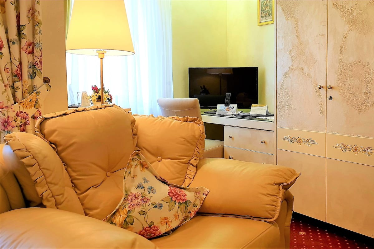 Une pièce avec un canapé beige, un téléviseur, une armoire et un panier posé sur un comptoir.