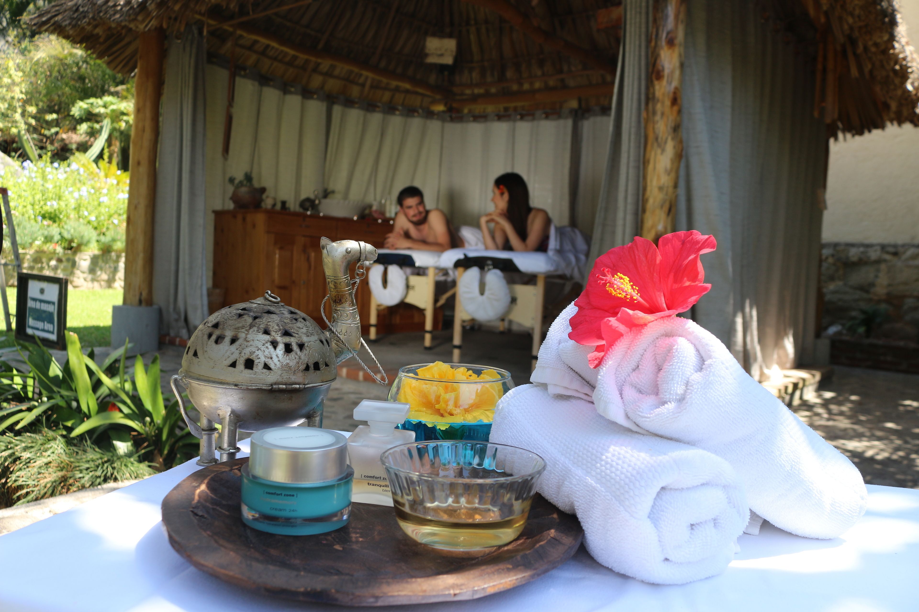 A spa setting with a wooden tray holding a teapot, a bowl of bath salts, and a towel.