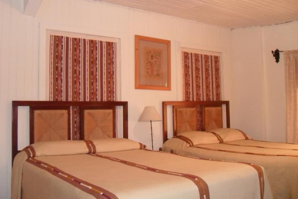 Habitación de hotel con dos camas, una lámpara y un cuadro en la pared.
