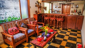 Una zona de bar con mobiliario de madera, suelo a cuadros y una barra con botellas.