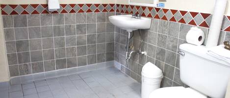 Un baño con lavamanos blanco, inodoro y toallero con una toalla.