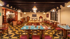 Un restaurante con suelo de cuadros, mesas y sillas de madera, y lámparas colgantes.