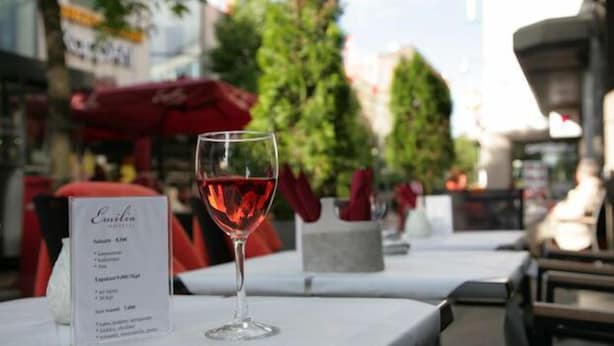 Une table avec un menu et un verre de vin rouge.