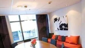 Une pièce moderne avec une table ronde, des chaises, un canapé et un grand tableau abstrait accroché au mur.