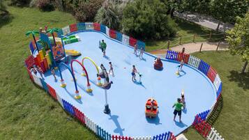 Un parco acquatico con piscina azzurra, strutture ludiche e un’area recintata.