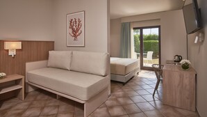 A modern hotel room with a sofa, a bed, a small desk, a TV, and a balcony with a view. - Torreserena Resort (Ginosa)
