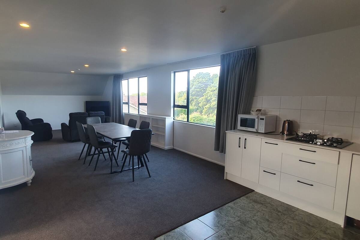 A modern kitchen with a dining area, white cabinetry, a microwave, and a gas stove.