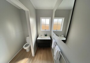 Un baño pequeño con inodoro, lavamanos y espejo.