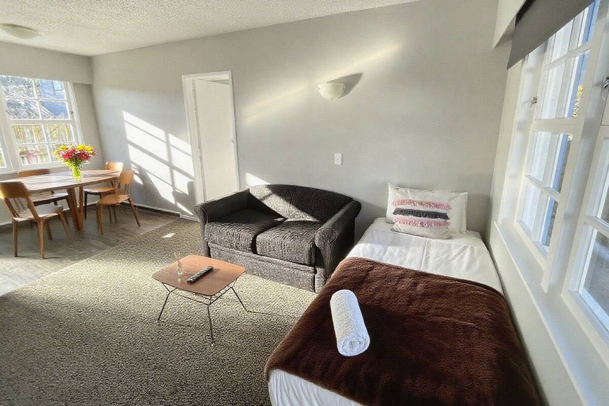 A living room with a sofa, a small table, and a bed.
