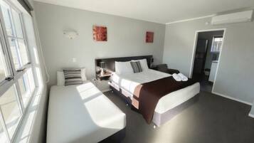 A hotel room with a bed, bedside table, lamp, and a bench.