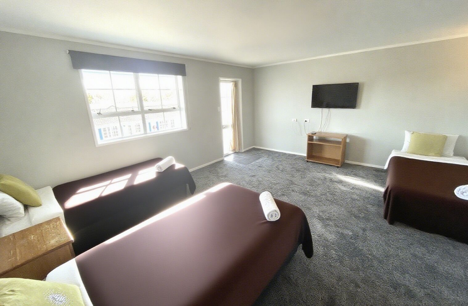 A hotel room with two single beds, a desk, a chair, a television, and a window with curtains.