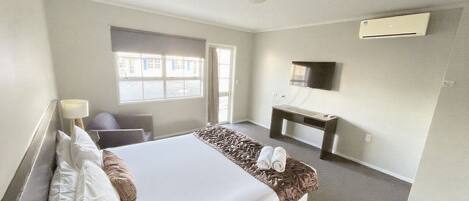 A hotel room with a bed, a desk, a chair, a TV, and a window.