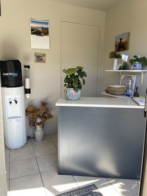 A reception area with a water dispenser, a potted plant, and a calendar on the wall. - Colonial Motel (Blenheim)