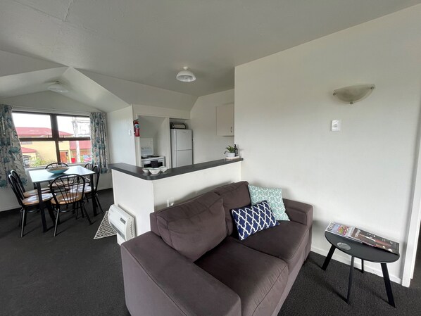 A compact living space with a kitchenette, a dining area, and a sofa.