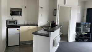 Cocina compacta con microondas, tostadora y refrigerador. Se ve también un lavamanos pequeño y una encimera.