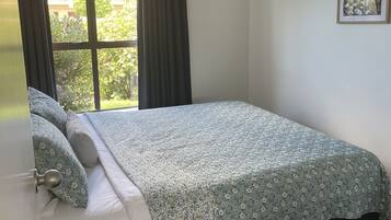 A bedroom with a bed, a small round table, and a window with curtains.