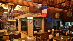 A restaurant with wooden interior, tables, chairs, and a sign for Grey Goose Vodka. - Hisham Hotel Amman (Amman)