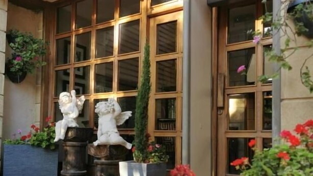 A building entrance with large windows, a flag, and potted plants. - Hisham Hotel Amman (Amman)