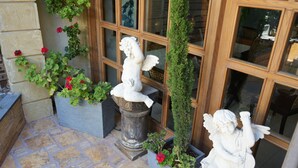 A stone-tiled patio with a statue of a seated figure and a column with a statue on top. - Hisham Hotel Amman (Amman)