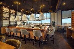 A bar area with a high bar, multiple stools, and pendant lighting. - Westcord WTC Hotel Leeuwarden (Leeuwarden)