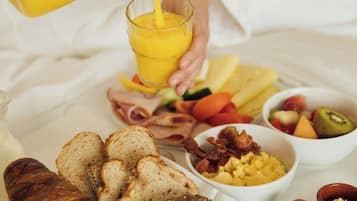 Desayuno con diversas opciones de comida y un vaso de jugo de naranja.