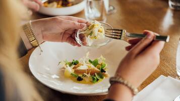 A person holding a fork with a dish of food on a plate.