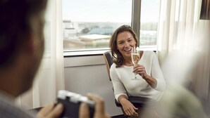 A person holding a glass of champagne in a room with a large window. - Westcord WTC Hotel Leeuwarden (Leeuwarden)