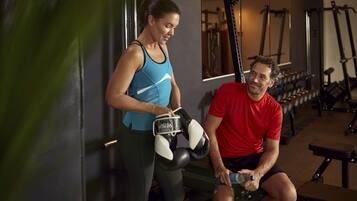 A gym with exercise equipment and a person sitting on a bench.
