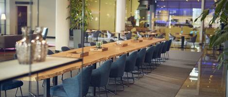 A modern conference room with a long wooden table, blue chairs, and glass partitions.