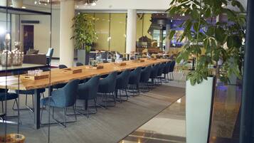 A long conference table with chairs, surrounded by glass walls and potted plants.