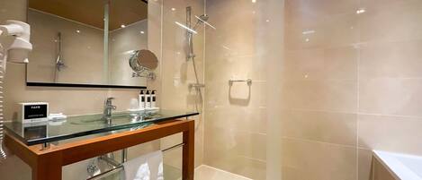 A modern bathroom with a glass vanity, a shower, and a large mirror.