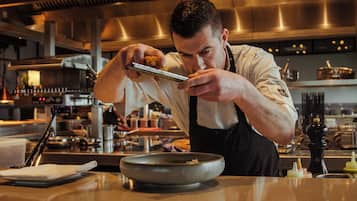Un chef en una cocina con paneles de madera, electrodomésticos de acero inoxidable y diversos utensilios de cocina.
